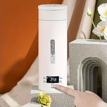 White portable kettle with digital display on a stone surface with flowers.
