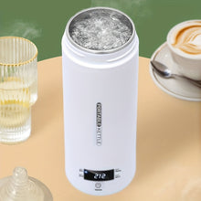 White portable kettle with digital display on a table with a cup of coffee and glassware.